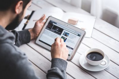 Homme consultant une tablette devant un café