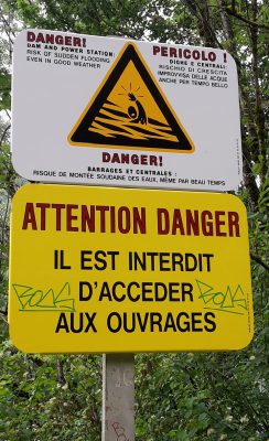 Un panneau routier de signalisation indique "Attention Danger Il est interdit d'accéder aux ouvrages"
