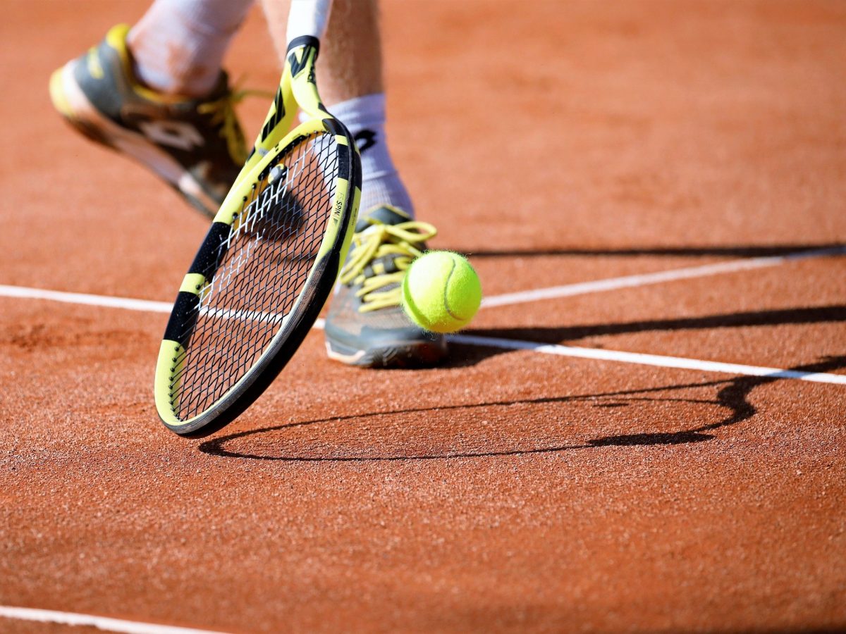 gros plan sur une balle de tennis une raquette et des baskets d'un joueur sur le terrain