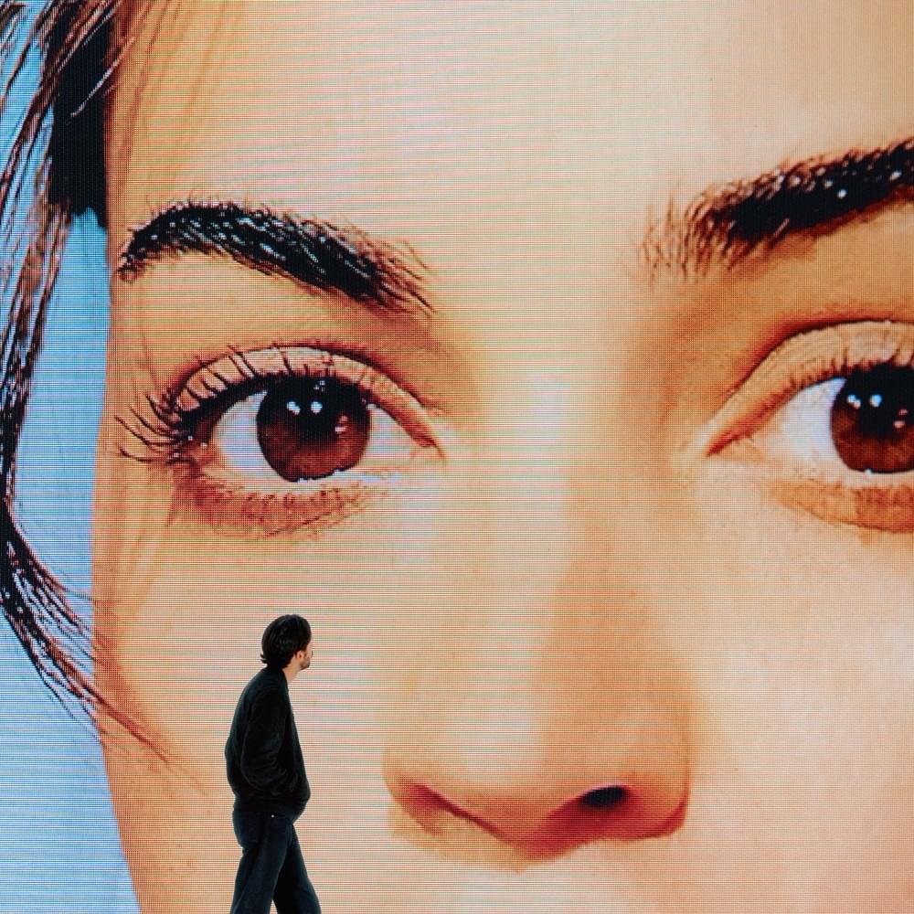 couverture de l'album Mauvais ordre, le rappeur marche devant un écran géant et regarde le visage en gros plan d'une femme